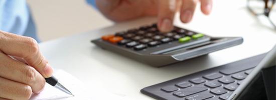 calculator, computer, and person holding a pen